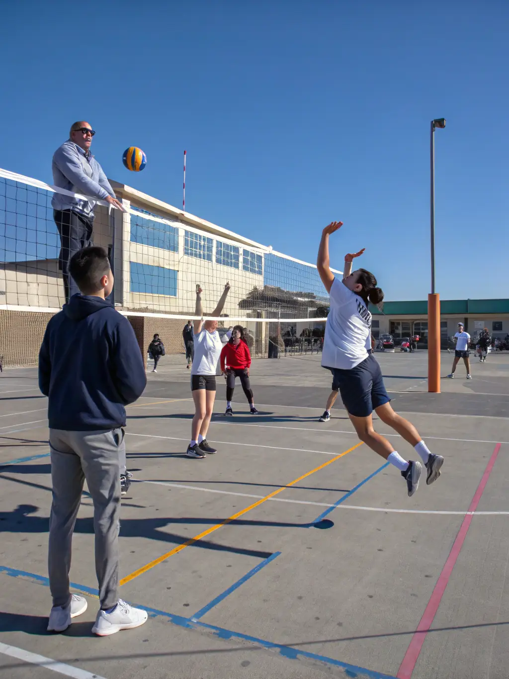 Students participating in a volleyball match outdoors, emphasizing agility and coordination.